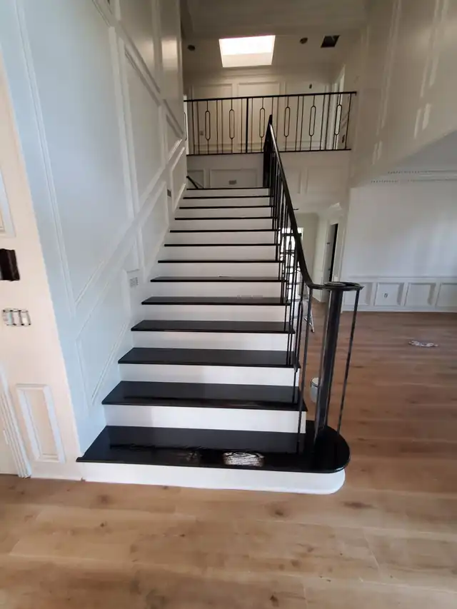 Staircase with dark stained treads, white risers and a black iron railing