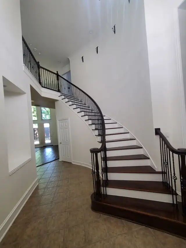 Sweeping curved staircase with dark stained treads and a black iron rail in an entry hall