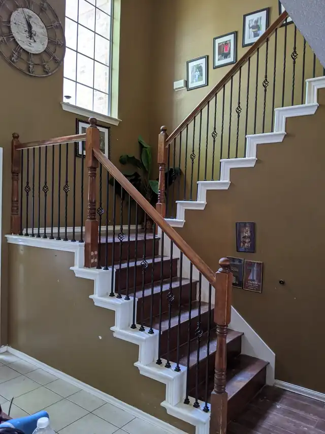 Iron balusters under a stained oak handrail on a stepped skirt