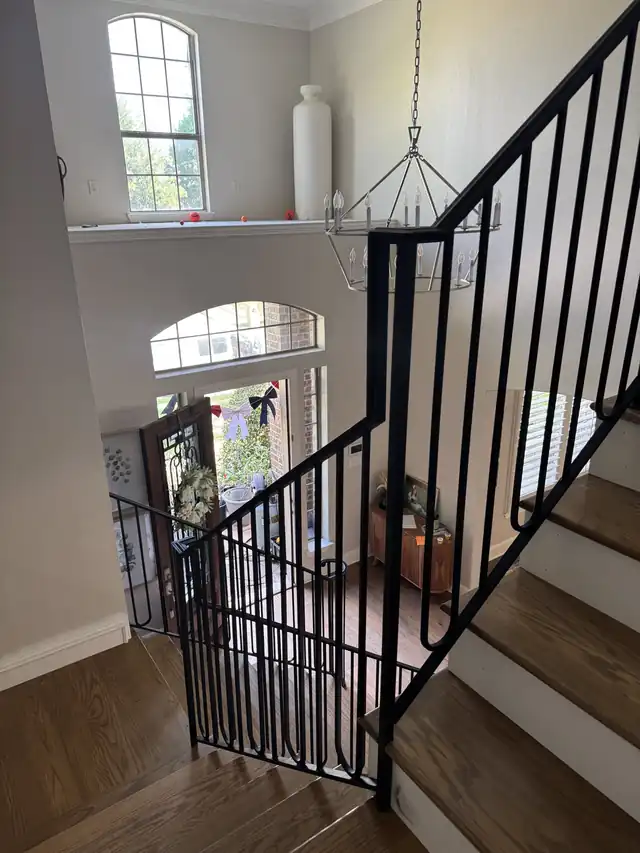 Black iron balustrade running up a staircase beside a tall window
