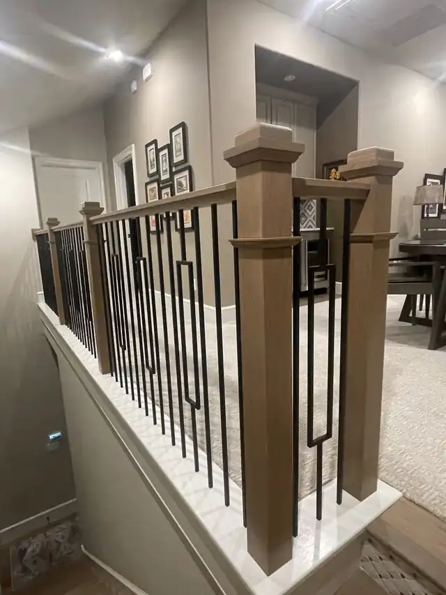 Stained oak newel posts framing a geometric iron panel
