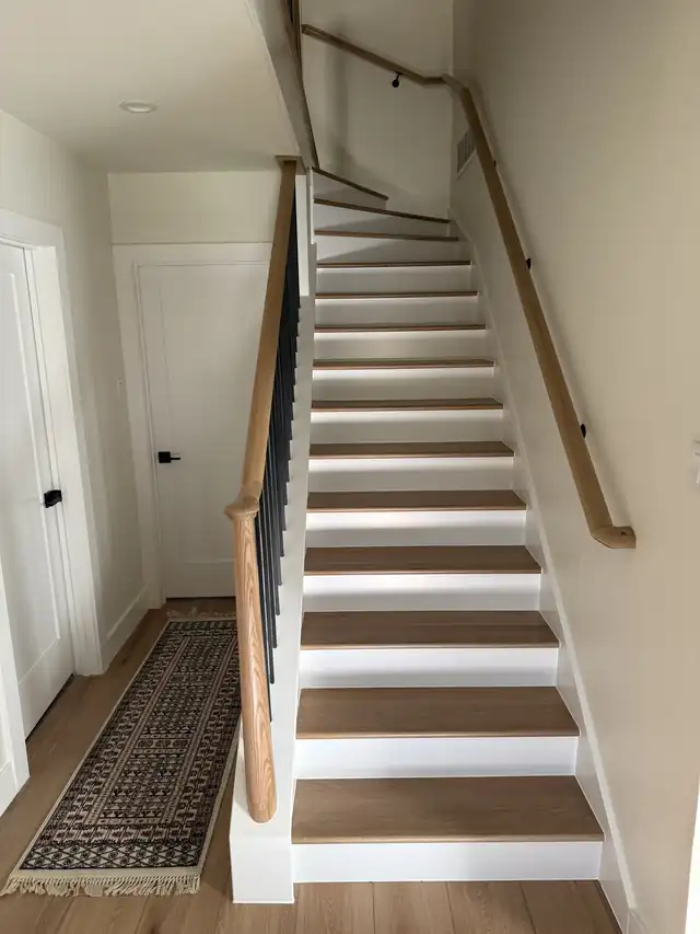 Stained oak handrail with iron balusters and white risers