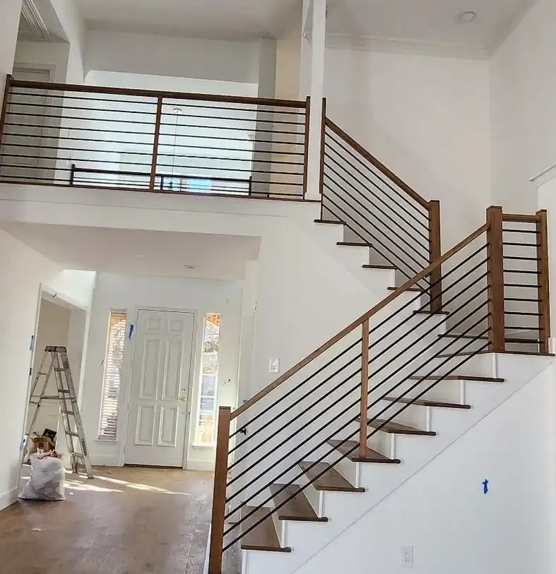 Oak staircase with a black horizontal-bar railing climbing to a two-storey landing
